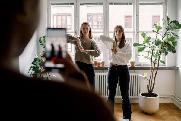 En person fotar två tjejer som gör en synkroniserad dans.