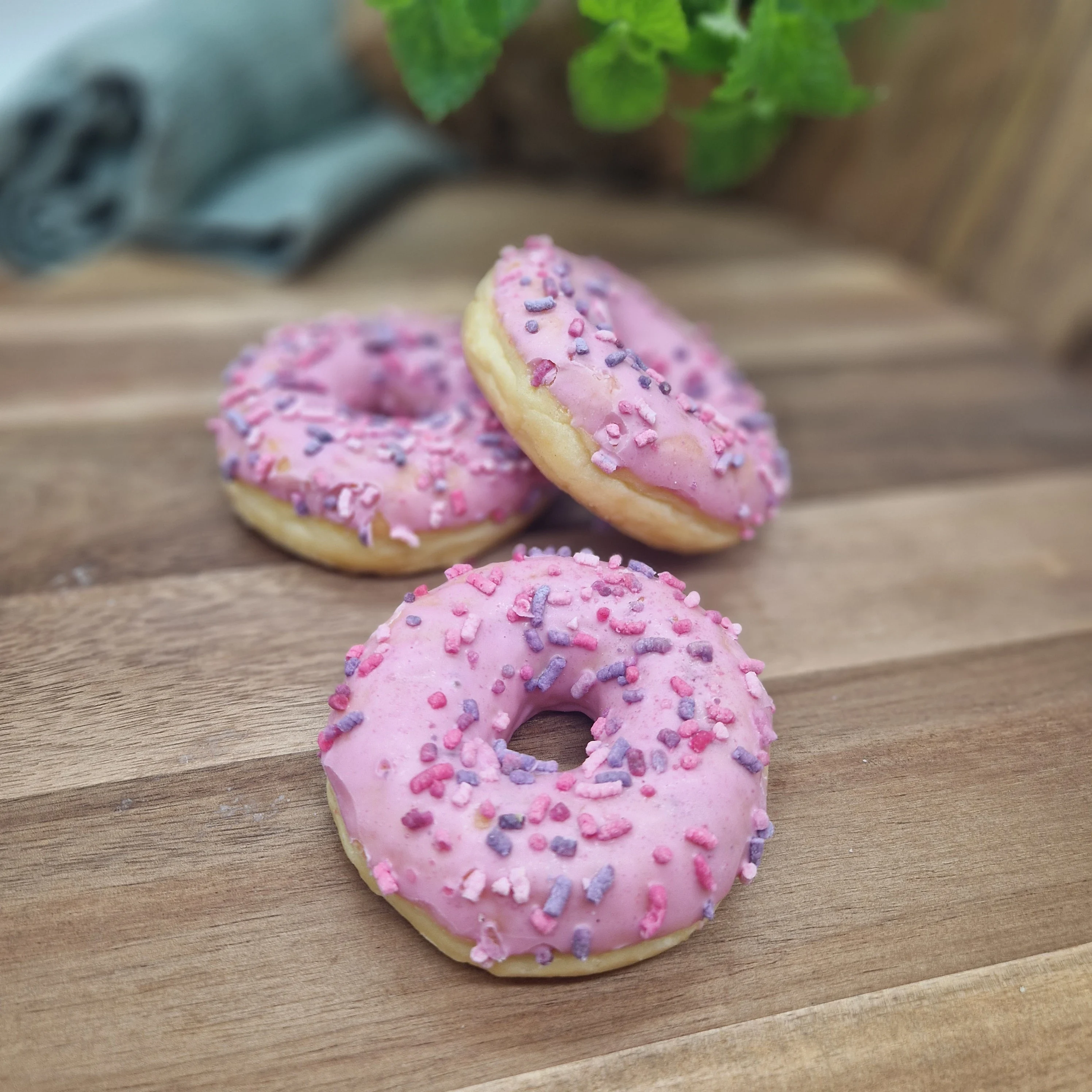 Rosa donut med strössel på träbricka. fikabord, fika