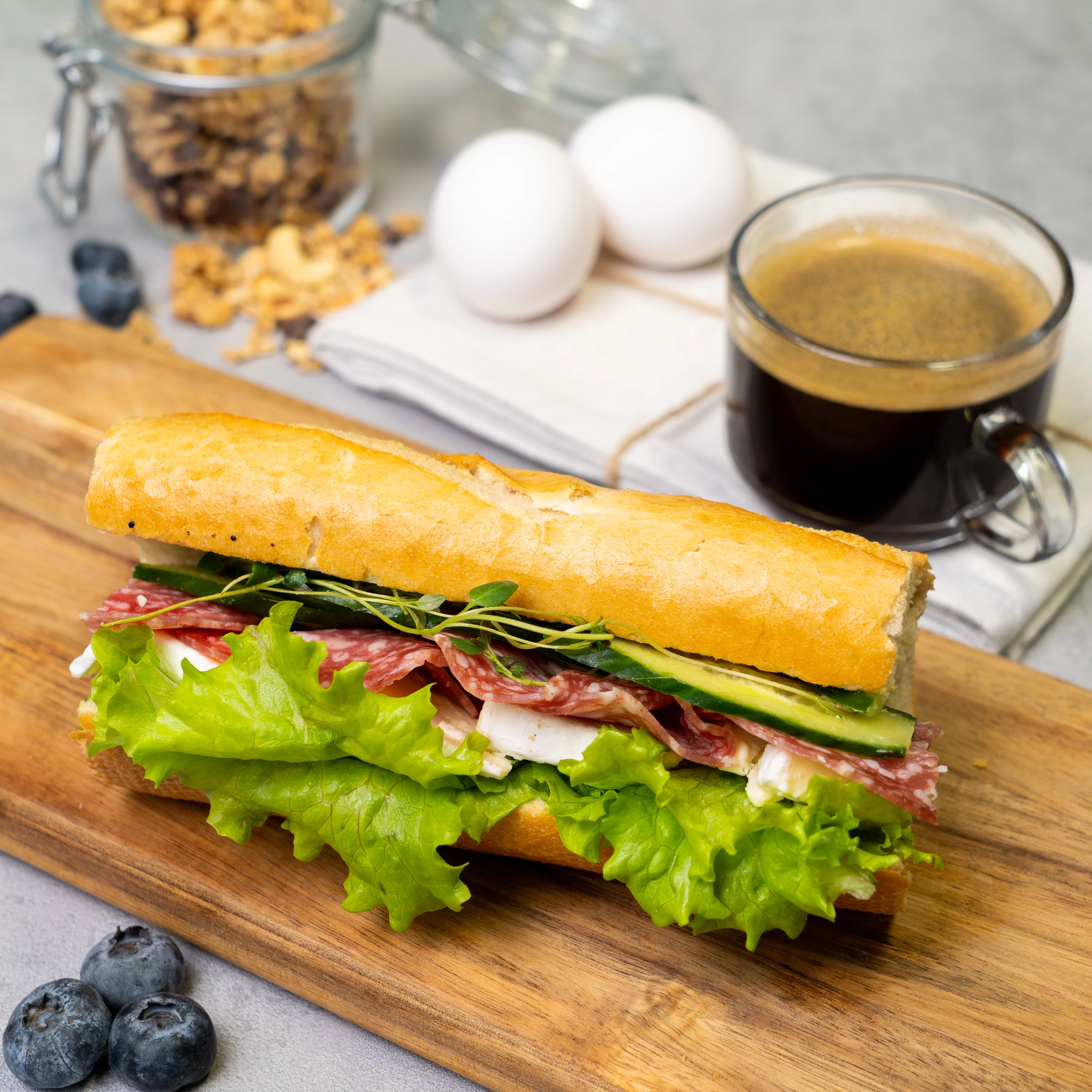 En baguette med brie-ost och salami, sallad och gurka.