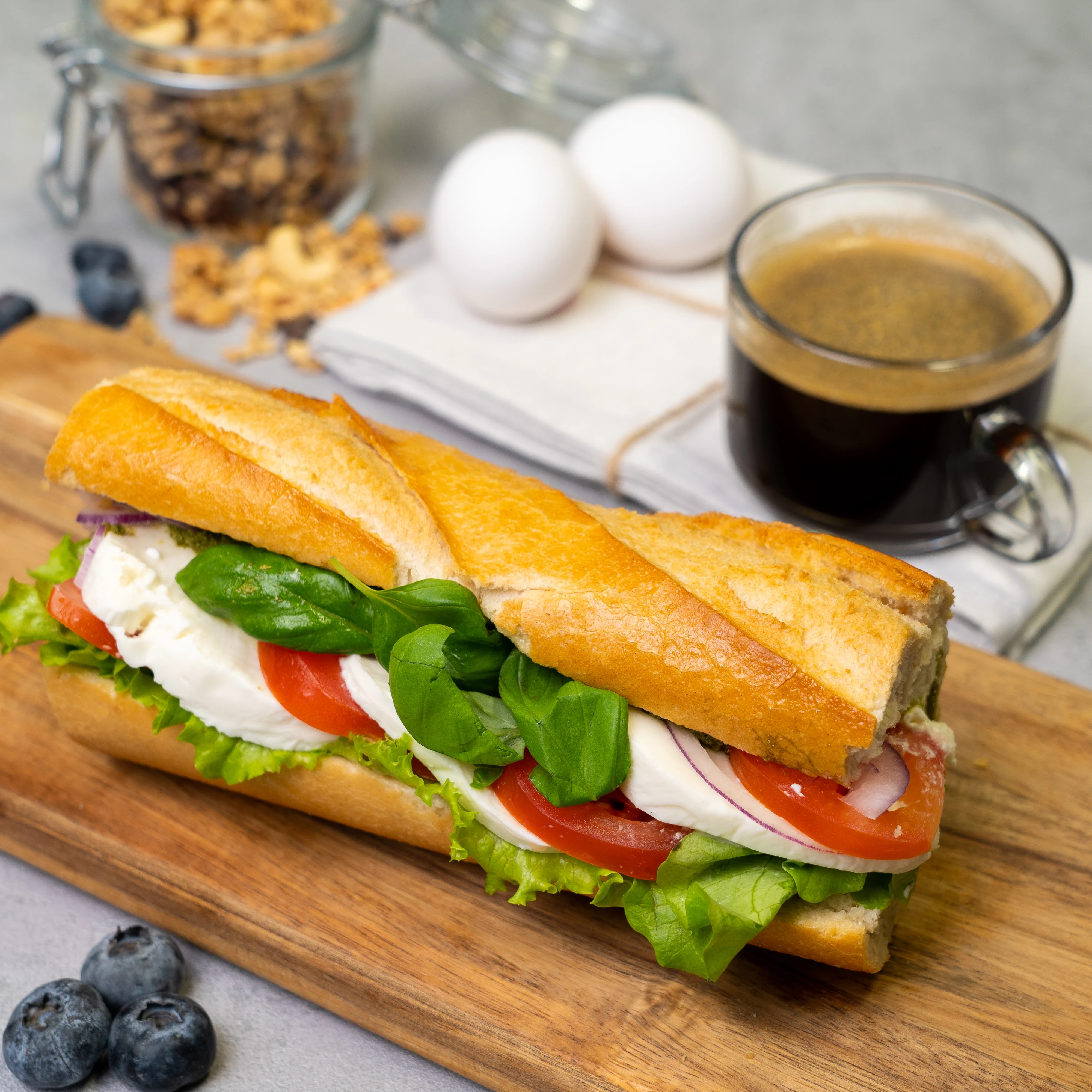 En baguette med mozzarella, tomat, pesto, sallad och rödlök.