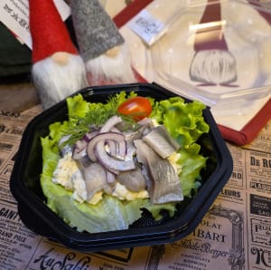 Sillsmörgås upplagd i form. Salladsblad i botten. Sillen ligger på en röra med västerbottenost.