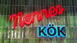 Grön kakelvägg med neonskylt "Nennes kök"