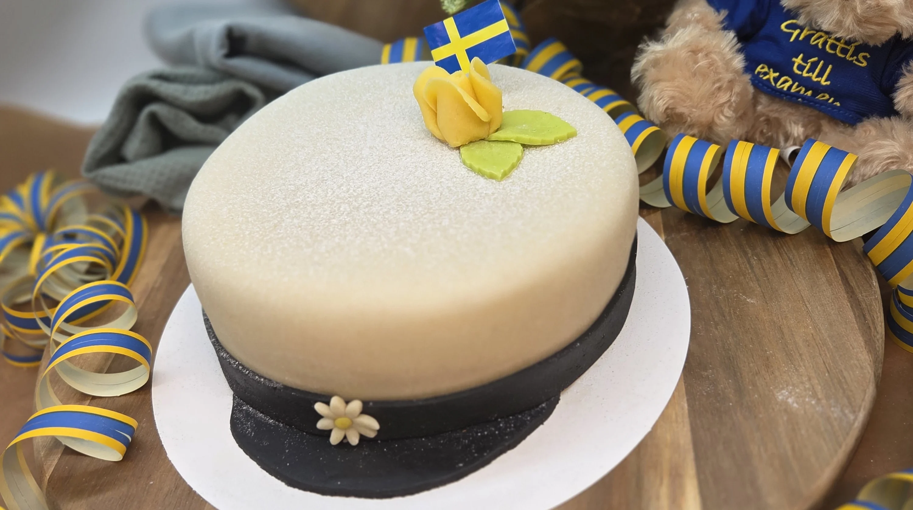 Studenttårta dekorerad med gul ros och flagga