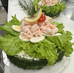 Liten rund smörgåstårta garnerad med ägg och räkor.