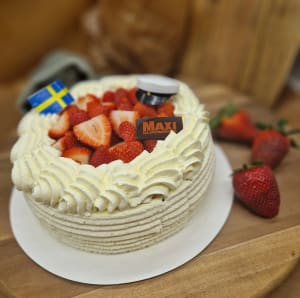 Jordgubbstårta med gräddrosetter, dekorerad med studentmössa och svenska flaggan