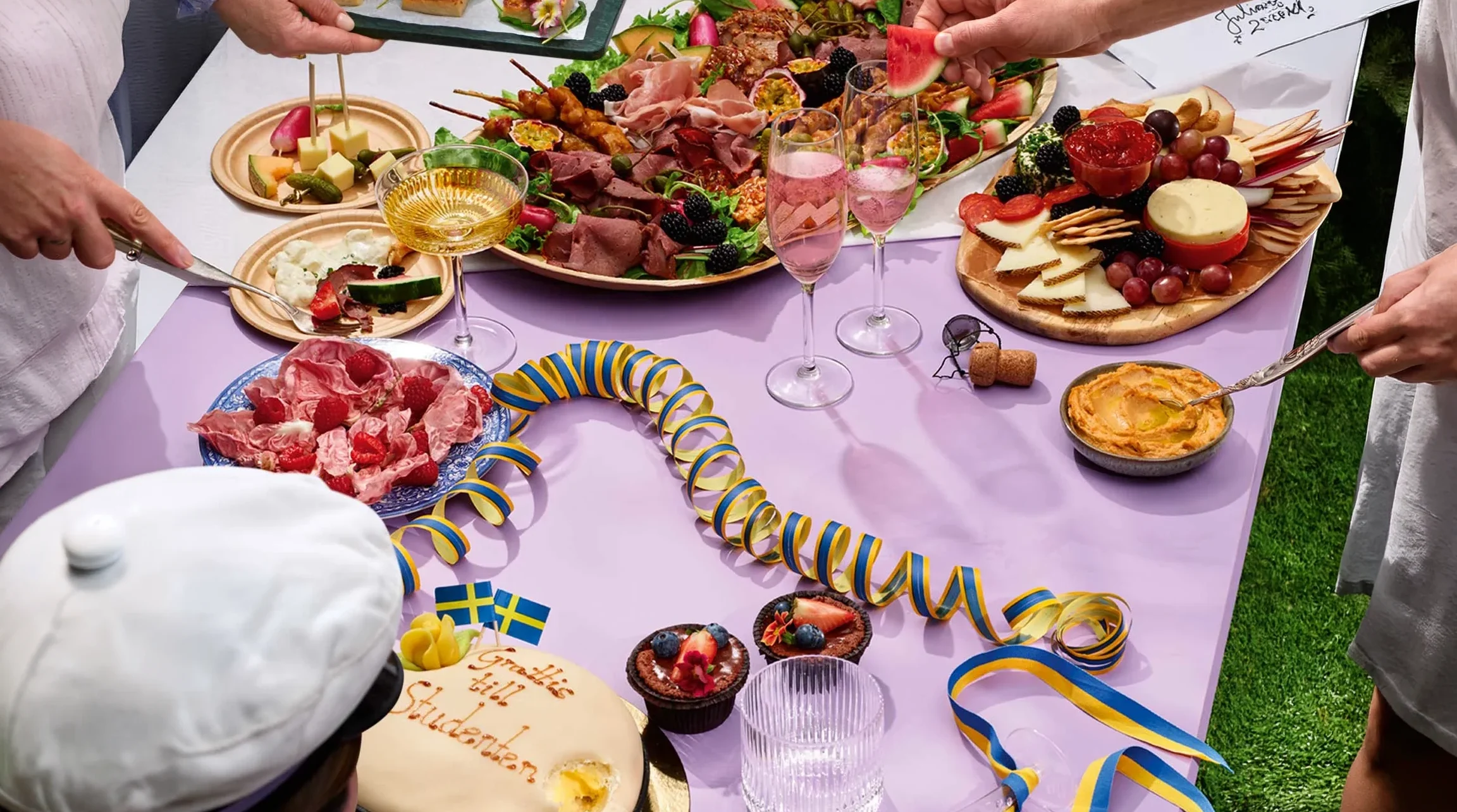 Bild på ett bord dekorerat i studenttema. Med mat, tårta, buffé osv.