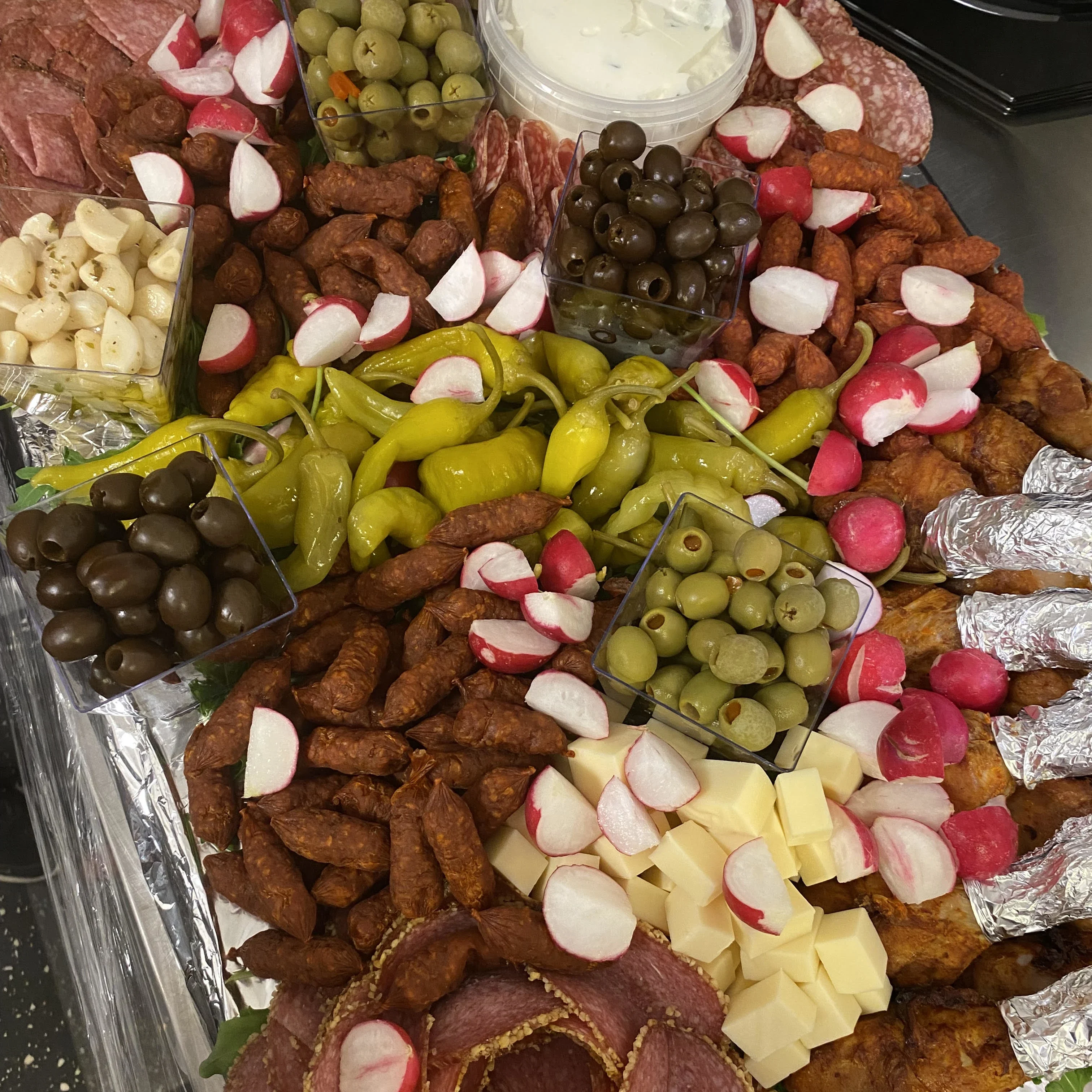 En bricka med en blandning av olika salami, ölkorv, oliver, ost och kycklingben