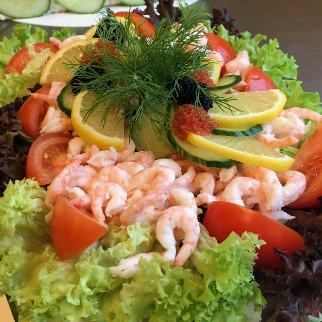 Smörgåstårta dekorerad med räkor, tomatklyftor, grönsallad, gurkskivor, citronskivor, svart och röd caviar och dill.
