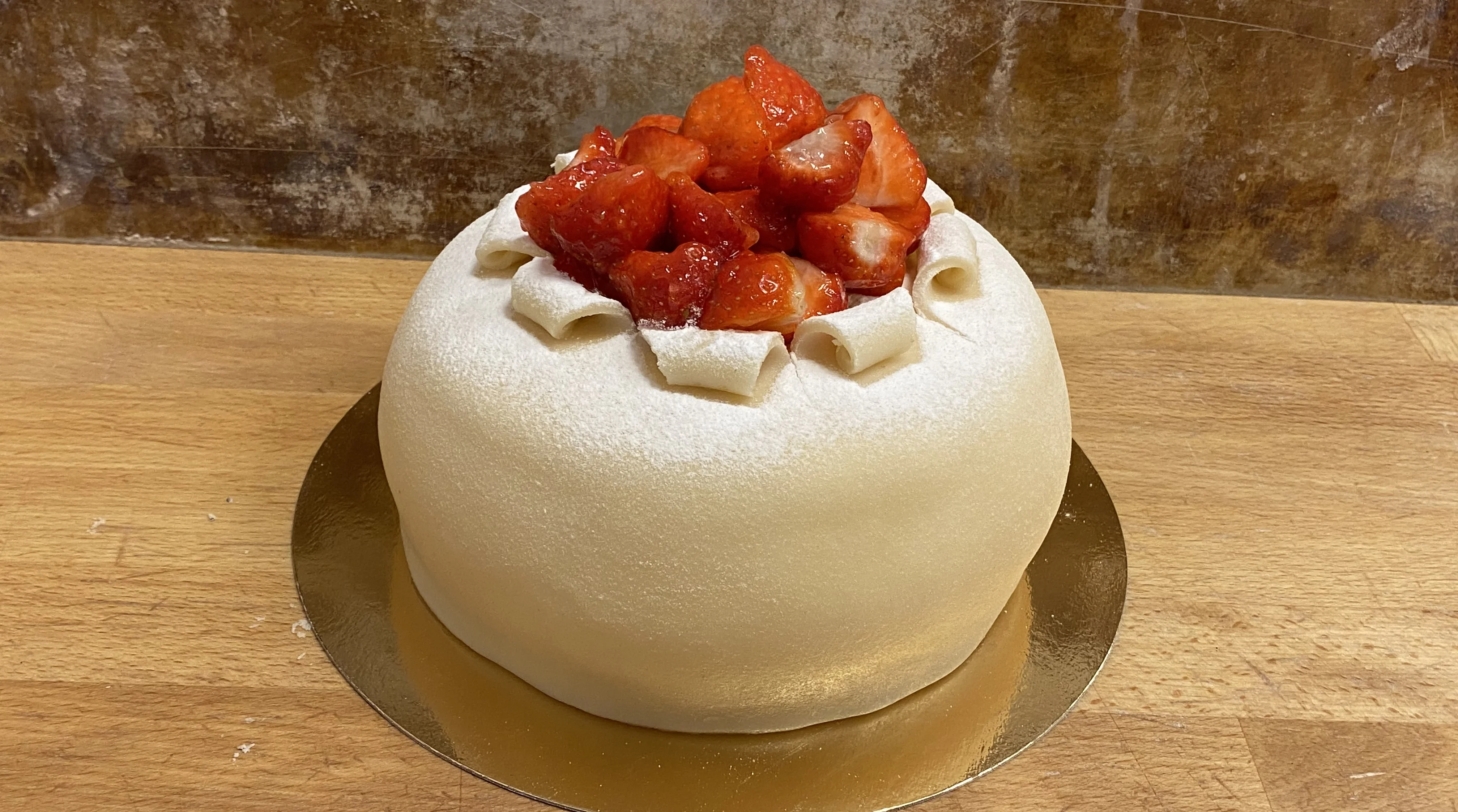 En jordgubbsprinsesstårta, vit marsipan med många jordgubbar på toppen.