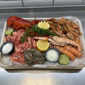En skaldjursplatå med ostron för 2 personer som innehåller 1 hummer, havskräftor, rökta- och färska räkor, ostron, baguette från vårt bageri, aioli och limeaioli, citron, lime och dill.