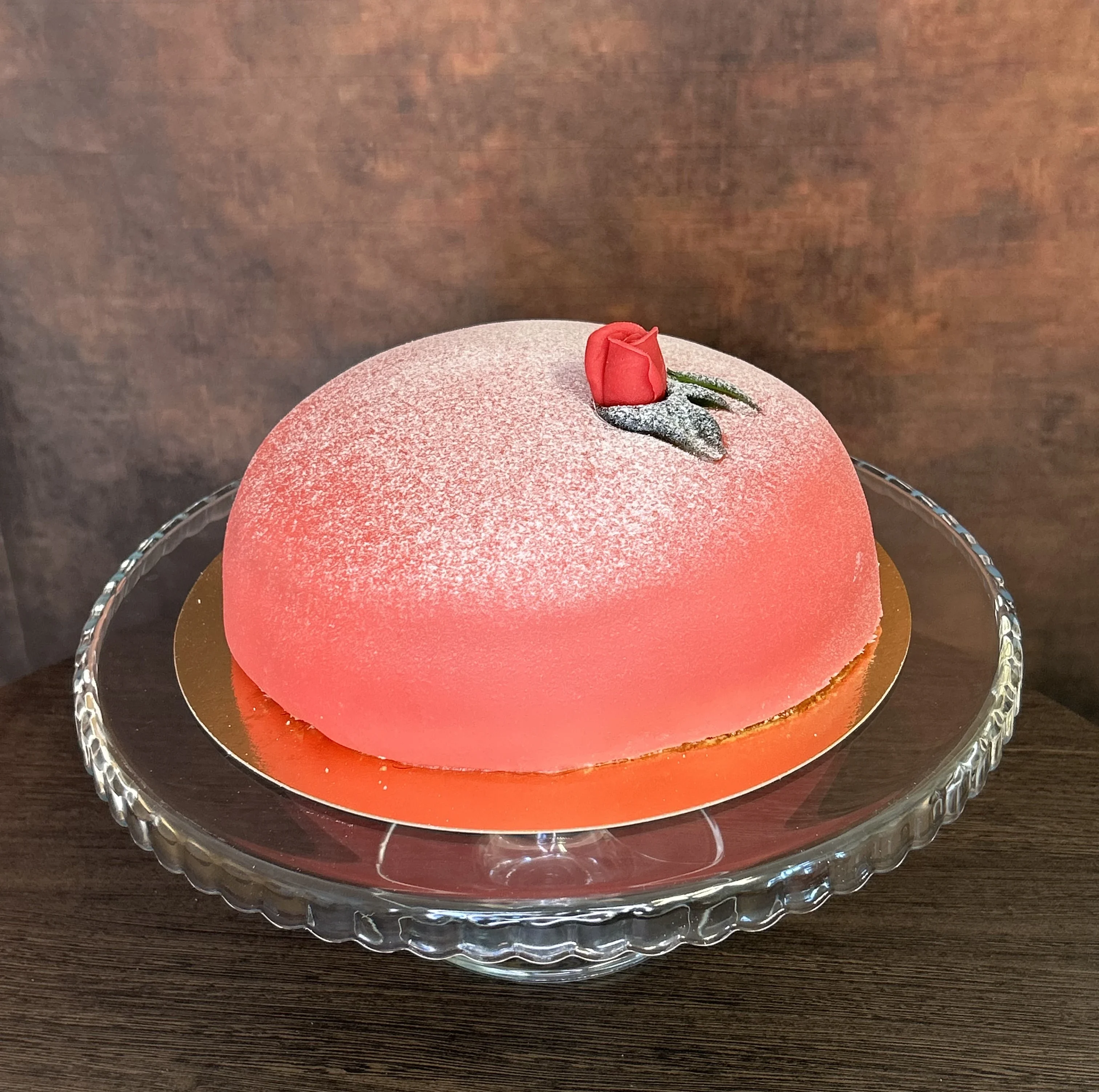 Här visas en operatårta med rosa/röd marsipan pyntad med en röd ros.