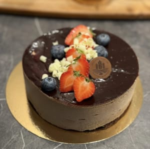 Chokladmoussetårta med chokladtårtbotten & hallonsylt,. Toppad med chokladgelé, vitchokladspån och färska bär.