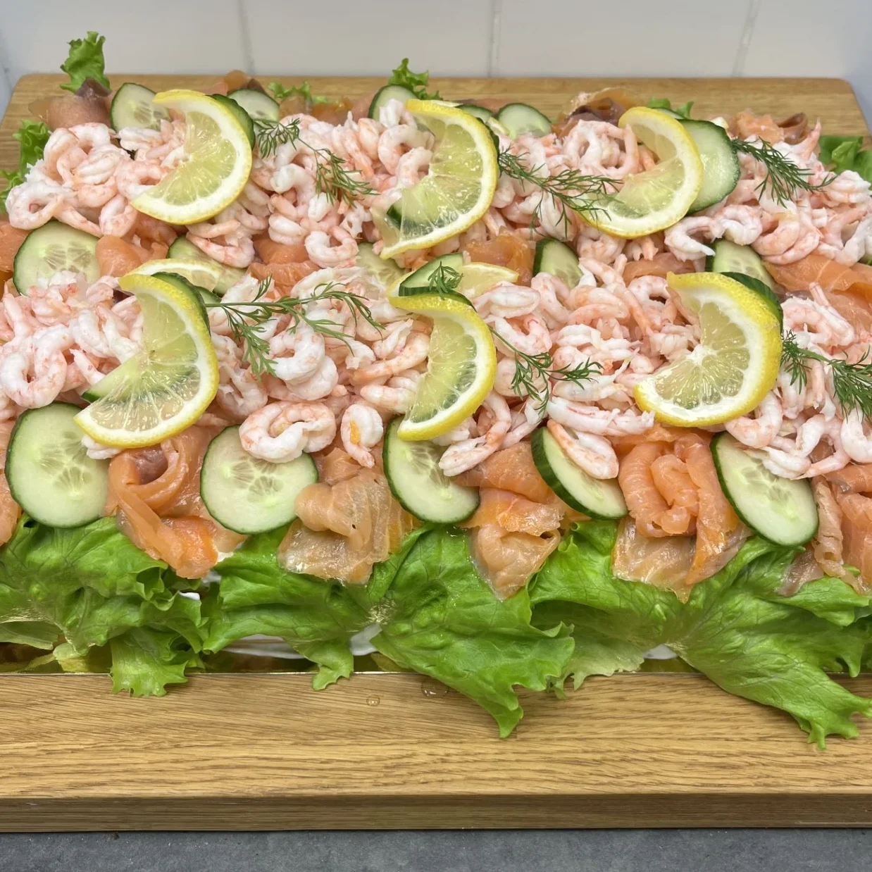 Smörgåstårta med kallröktlax och räkor. Sallad på sidorna. Garnerad med citron och dill.