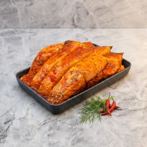 En generös portion grillad laxfilé glaserad med röd sweet chilisås, garnerad med färsk koriander och serverad med en klyfta citron.
