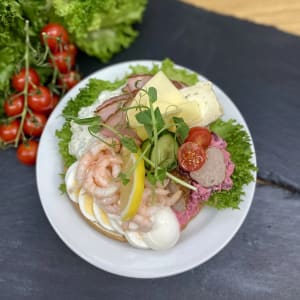 En rund smörgås med ägg, räkor, skinka, potatissallad, köttbullar, rödbetssallad, ostar samt grönsaker