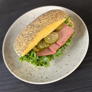 Ljus fralla toppade med vallmofrön, fylld med skivad leverpastej, inlagd gurka och salladsblad