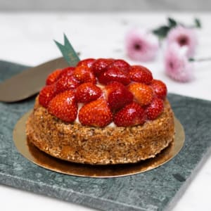 Mandelsockerkaksbotten som är urgröpt och fylld med jordgubbssylt, grädde och vaniljkräm. Heltäckt med jordgubbar och gelé.