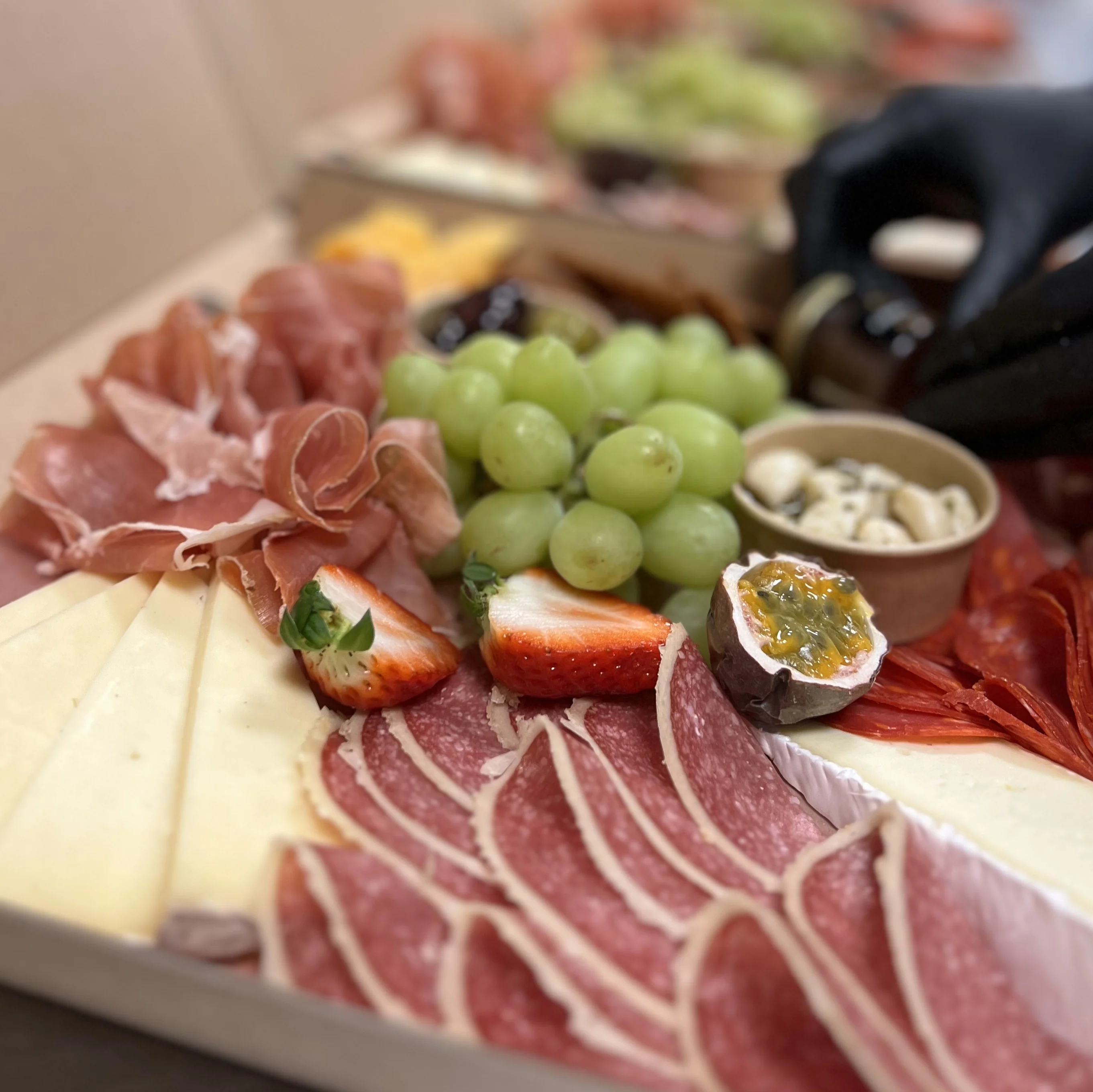 Tapaskartong. Salami, ost, kex, marmelad, frukt, inläggningar.