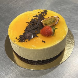 Moussetårta med smak av mango, dekorerad med choklad och frukt