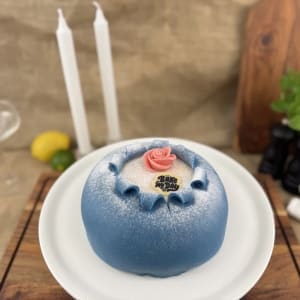 Blå marsipankupol på sockerkaksbotten, fylld med crème chantilly och blåbärssylt. Fint rekorerad med marsipanros.