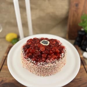 Frisk hallonmousse på sockerkaksbotten, toppad med hallon och gelé. Kanterna är täckta med kanderade rispuffar.