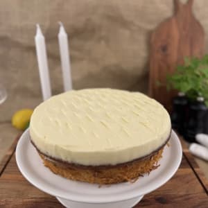 Saftig morotskaka med ett tjockt lager cream cheese-topping. Dekorerad med sockerkokade, färskrivna morötter.
