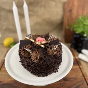 Mörk härlig chokladbotten med len chokladmousse och kanter med hyvlad mörk choklad. Dekorerad med kakao, chokladkvadrater och marsipanros.