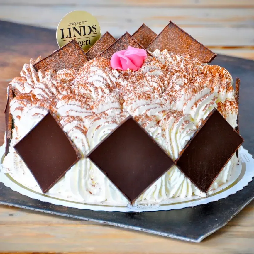 Marängbottnar med hasselnötter och grädde. Dekorerad med mörk choklad, kakao och marsipanros.