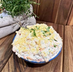 Skål med västerbottenskagen toppad med riven västerbotten och timjan, ståendes på ett fat