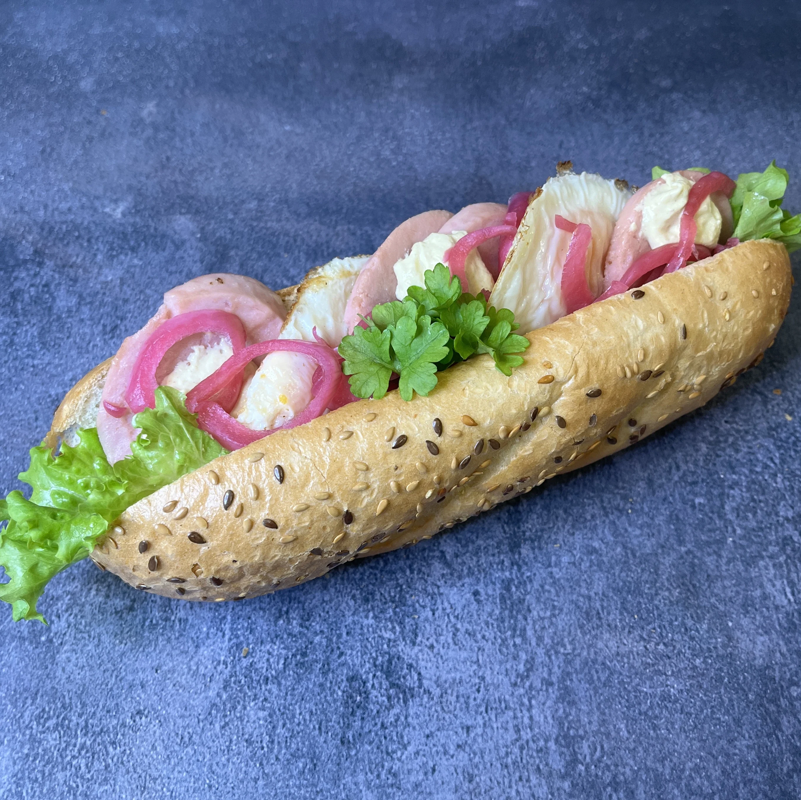 Baguette fylld med falukorv och ägg. Toppad med rödlök och persilja.