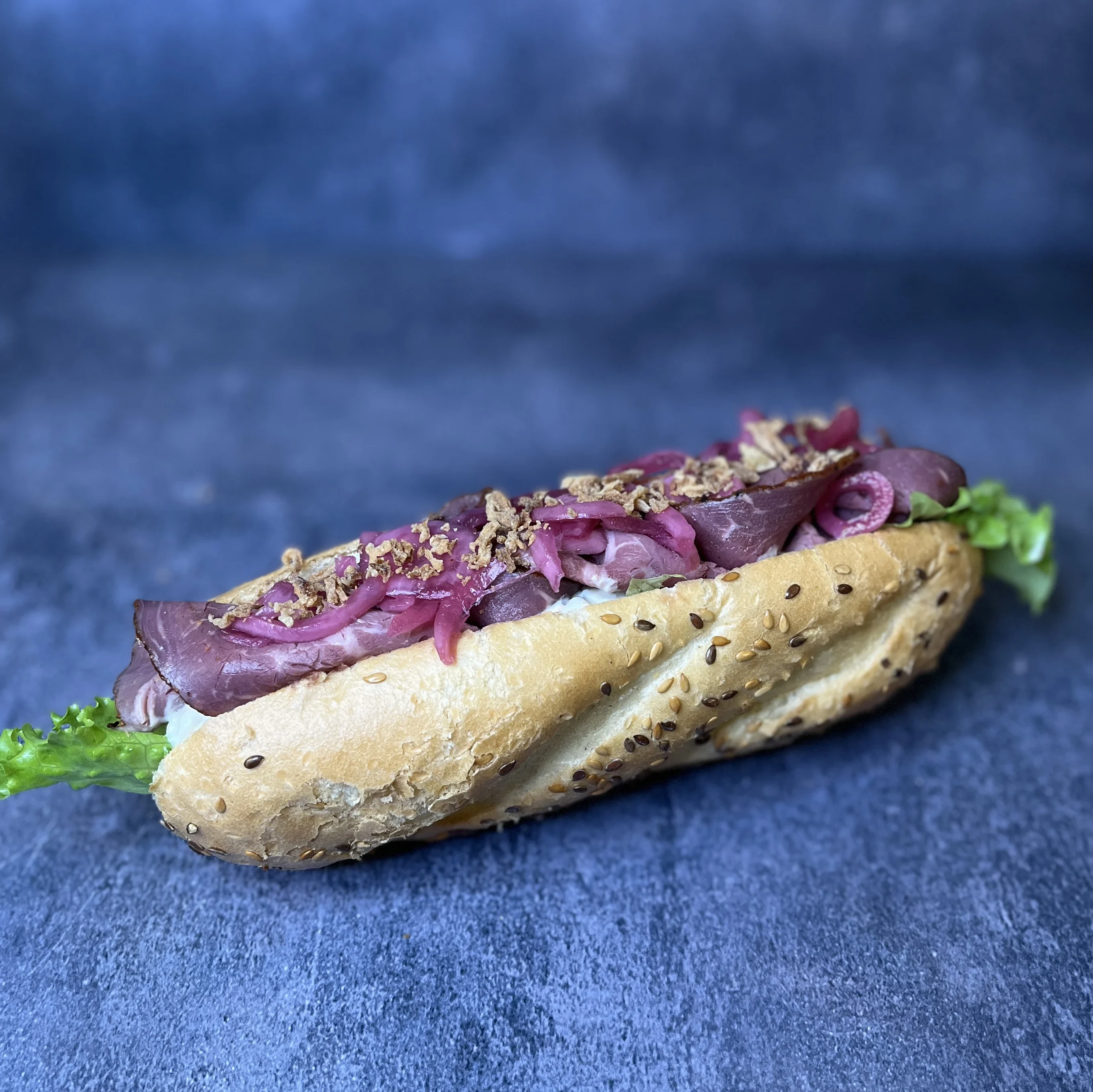 Baguette med rostbiff, potatissallad, picklad rödlök, toppad med rostad lök.