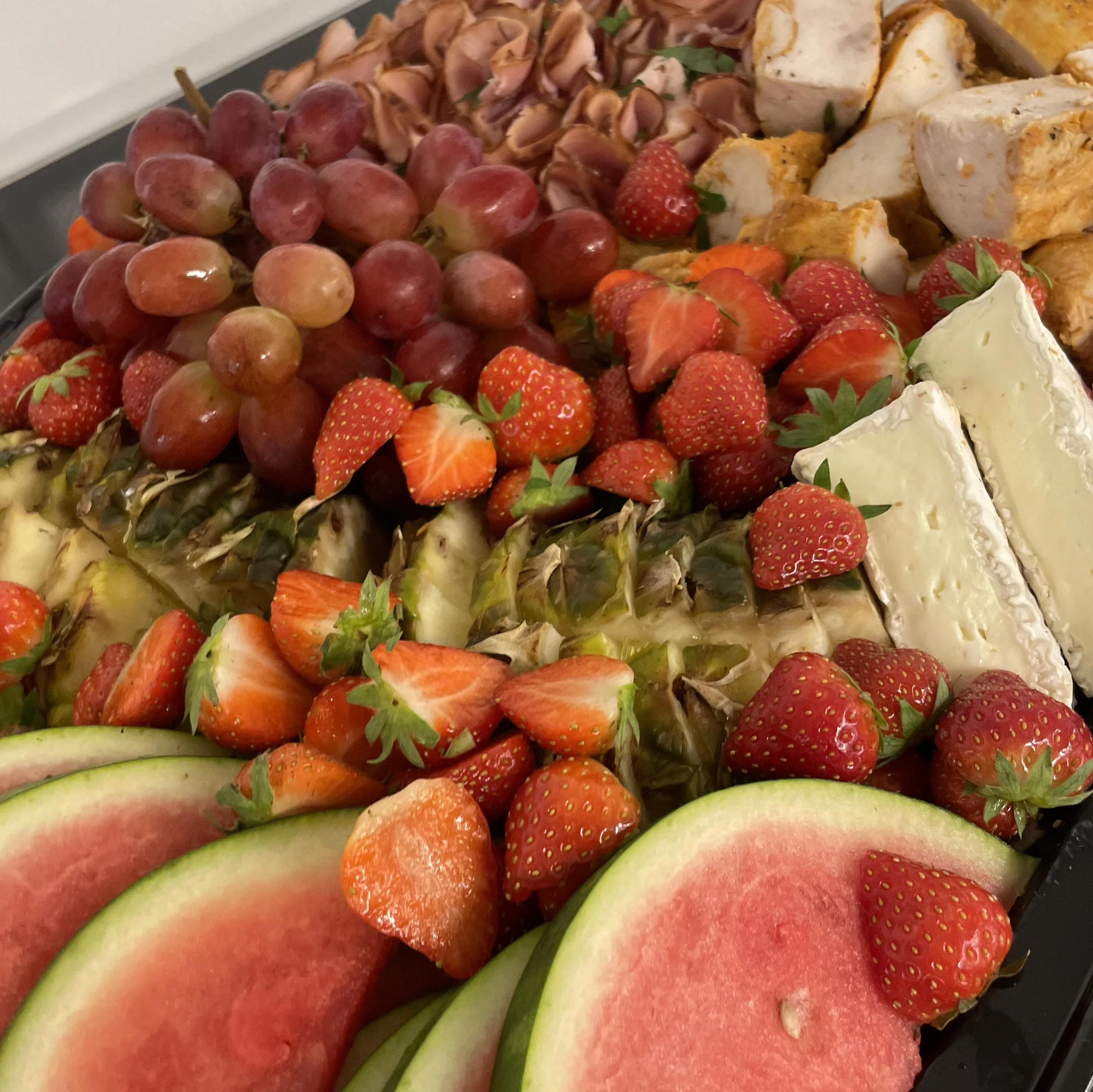 Fat med vattenmelon, ananas, jodgubbar, brie, vindruvor, skinka, kyckling och persilja.