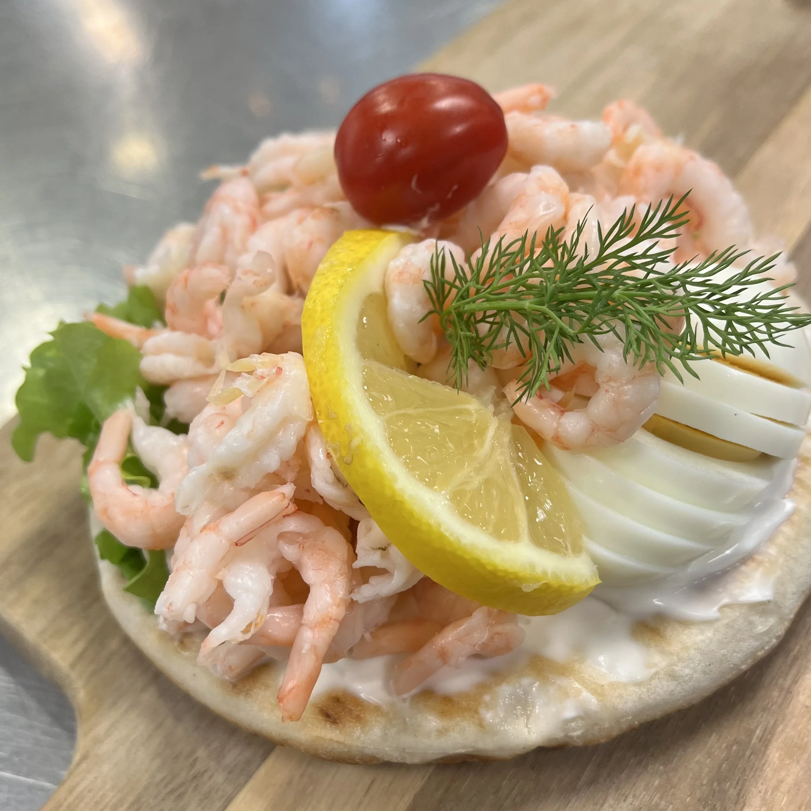 Vår underbara räksmörgås med en generös mängd handskalade räkor på, ett kokt skivat ägg, som vilar fint på en Hällakaka bredd med majonnäs och ett salladsblad. Som dekoration har vi den passande citronskivan, tomaten och dillkvisten.