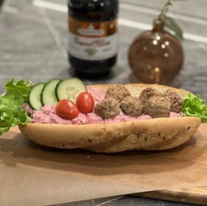 Baguette fylld med krämig rödbetssallad toppad med köttbullar & grönsaker.