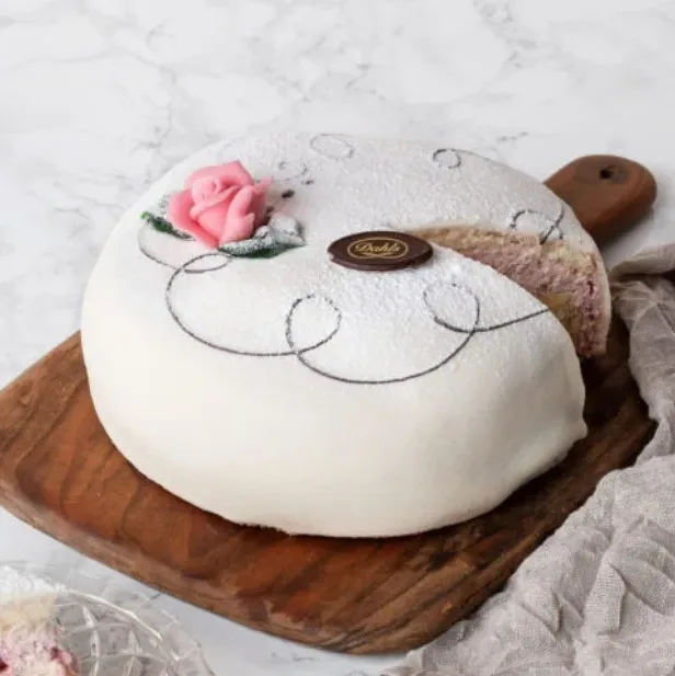 Oskuldsfull och vacker i vit marsipan. Mellan tre hembakta sockerkaksbottnar samsas vår egna vaniljkräm och fluffig grädde och rikligt med hallon. Vår rekommendation