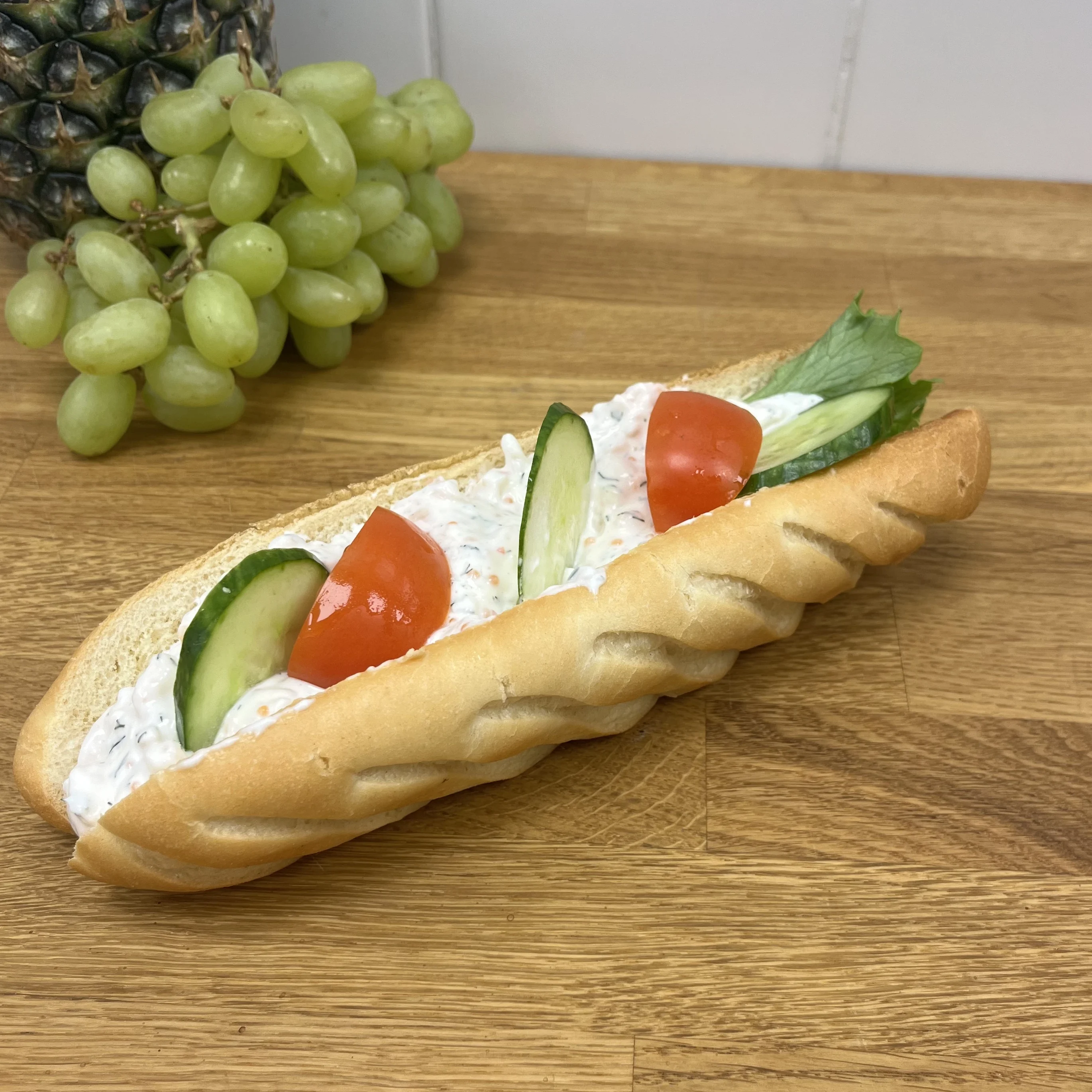 baguette med skagenröra, dekorerad med gurka och tomat.