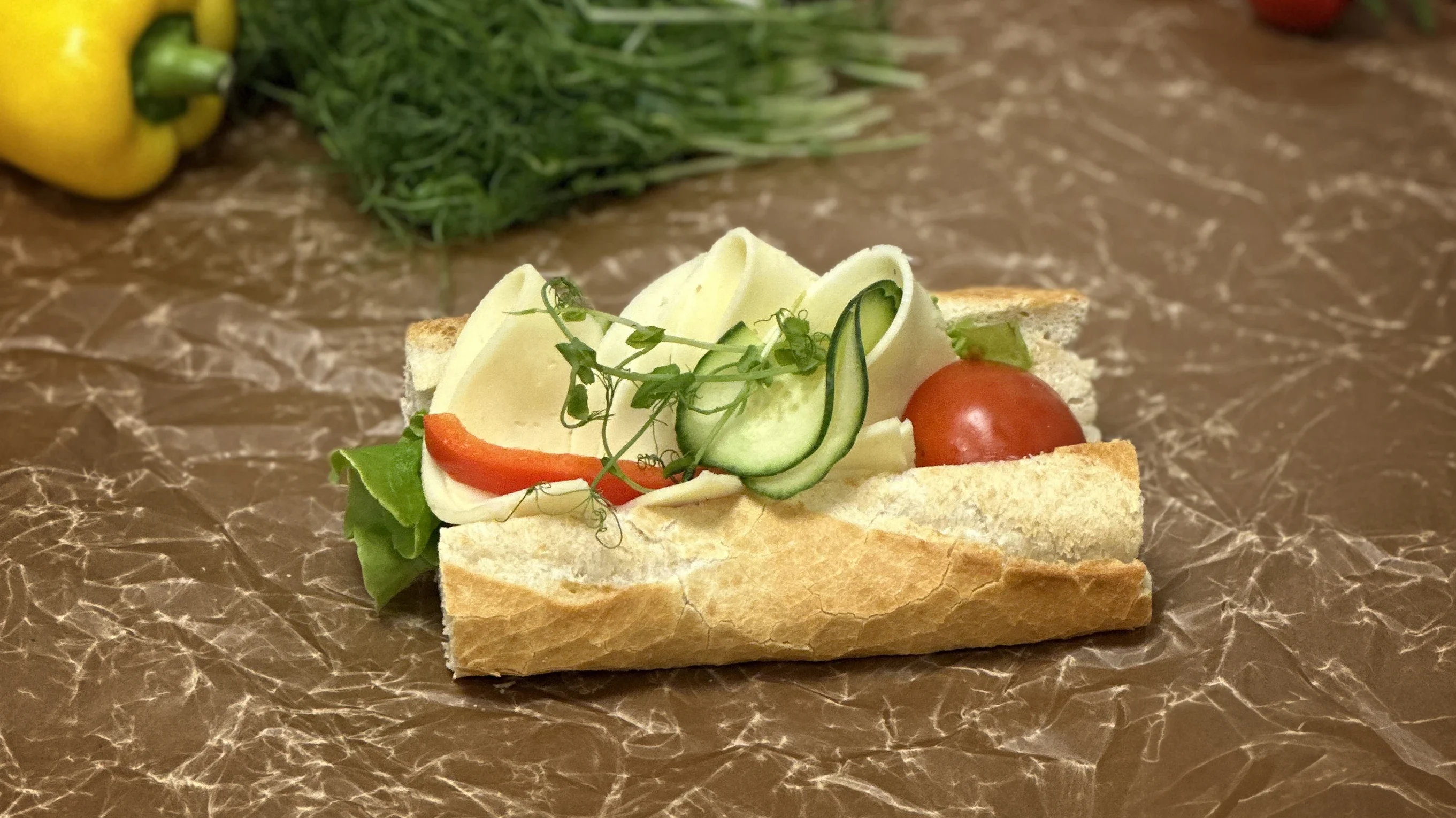 Baguette med ost, tomat, gurka, paprika och ärtskott.