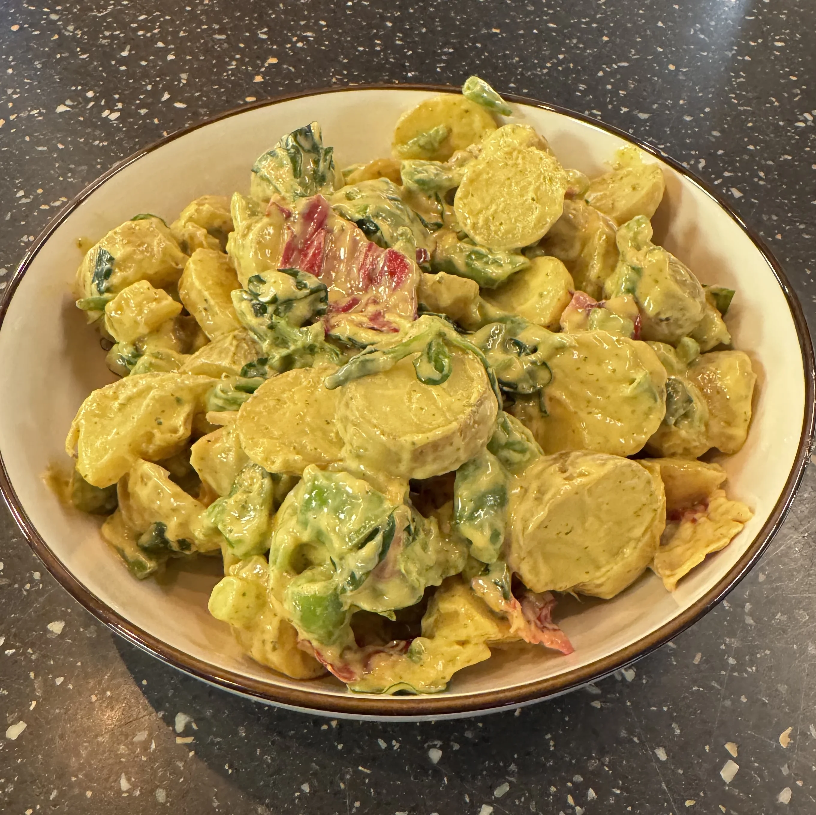 En skål med Fransk potatissallad. En Senapsbaserad Sallad med Färskpotatis, Spenat, Rödlök & sockerärtor.