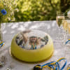 Gräddtårta med grön marsipan och ett foto på en student iförd studentmössa och blågula band. Tårtan står på festdukning med vilda blommor, glas med mousserande dryck och blågula band.