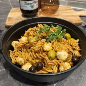 Pastasallad med italienska smaker fylld med krämiga mozzarellabollar, oliver och soltorkadetomater