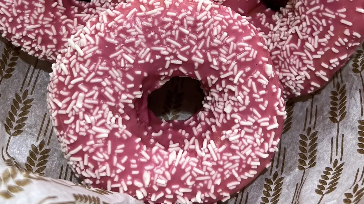 Donut med jordgubbsglasyr toppad med vit choklad strössel