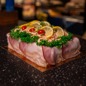 En smörgåstårta garnerad med skinka, räkor, krispsallat, citron, gurka och tomat