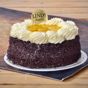 Rund tårta men nedre delen täckt av chokladströssel. Övre delen är gjord av spritsad grädde i en rund ram med skivade bananer i mitten av tårtan.