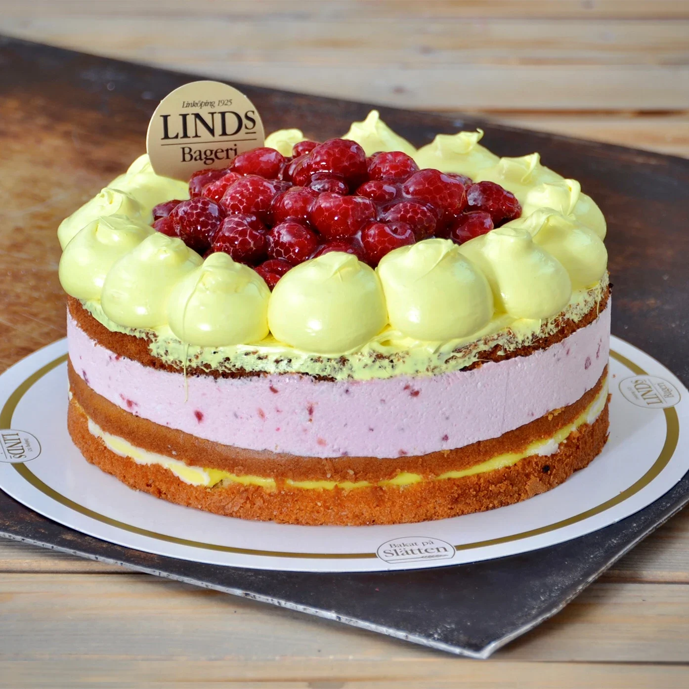 Sockerkaka, hallonmousse och citronkräm. Dekorerad med hallon i gelé. (Innehåller: Gluten. Innehåller ej Laktos, Mandel, Nötter, Mjölk & Ägg)