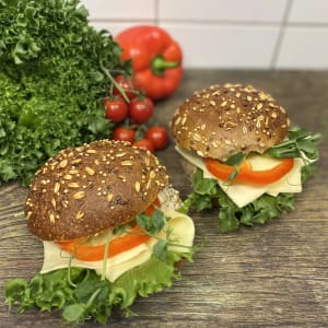 Två mörka frallor fyllda med ost och grönsaker