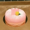 Rosa prinsesstårta med en prinsesskrona stämplad i mitten på tårtan. Toppad med en gul marsipanros i den högra nedre delen av kronan
