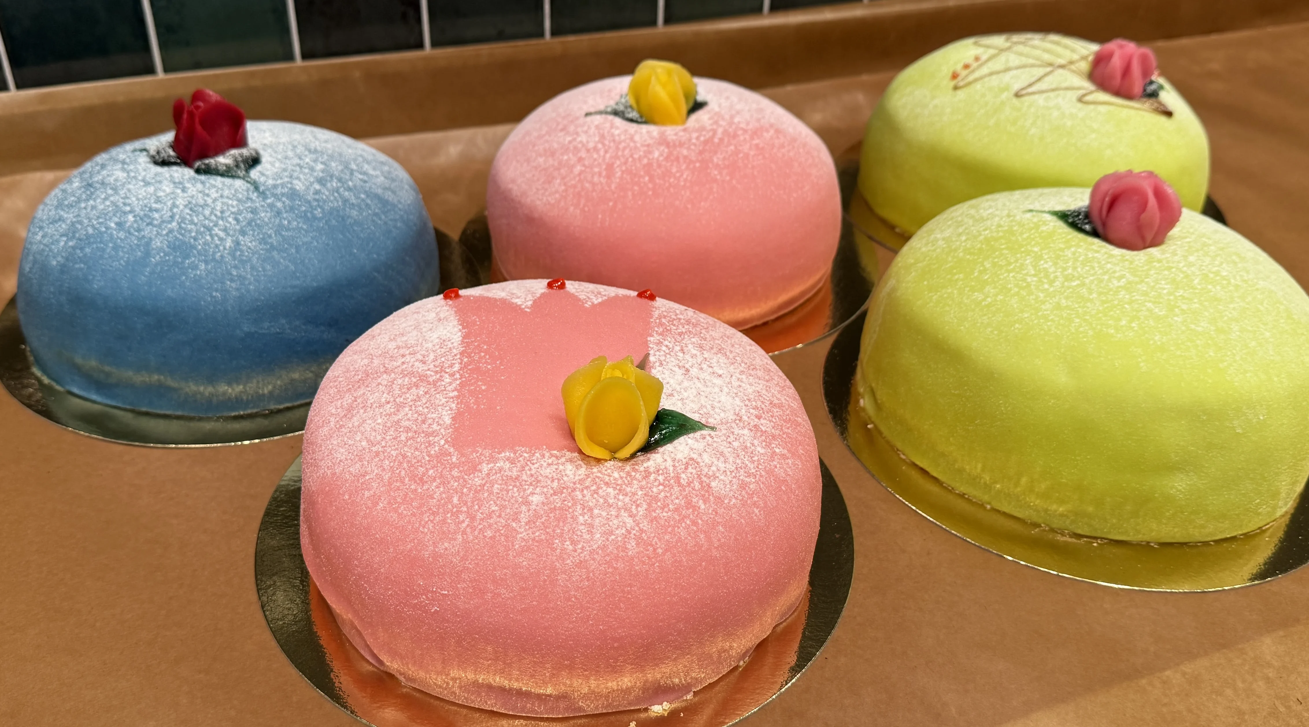 fem olika marsipantårtor i tre olika färger, rosa, blå och grön