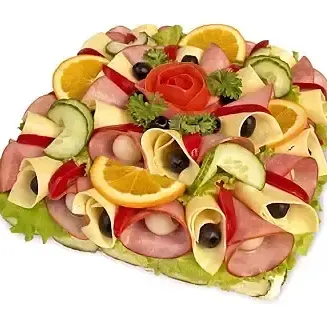 smörgåstårta som är dekorerad med rökt skinka, ostskivor, tomatklyftor, apelsinskivor, gurkskivor, persilja, röda druvor, rödpaprika, grönsallad.