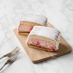 Mellan tre hembakta sockerkaksbottnar samsas vår egna vaniljkräm och fluffig grädde och rikligt med hallon.