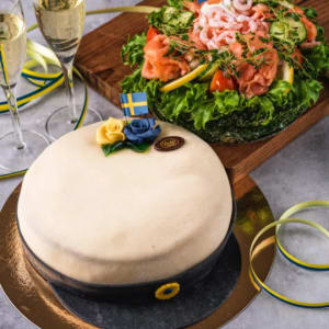 Under marsipantäcket döljer sig hembakade sockerkaksbottnar varvade med len nyvispad grädde, hemkokt vaniljkräm och hallonsylt.